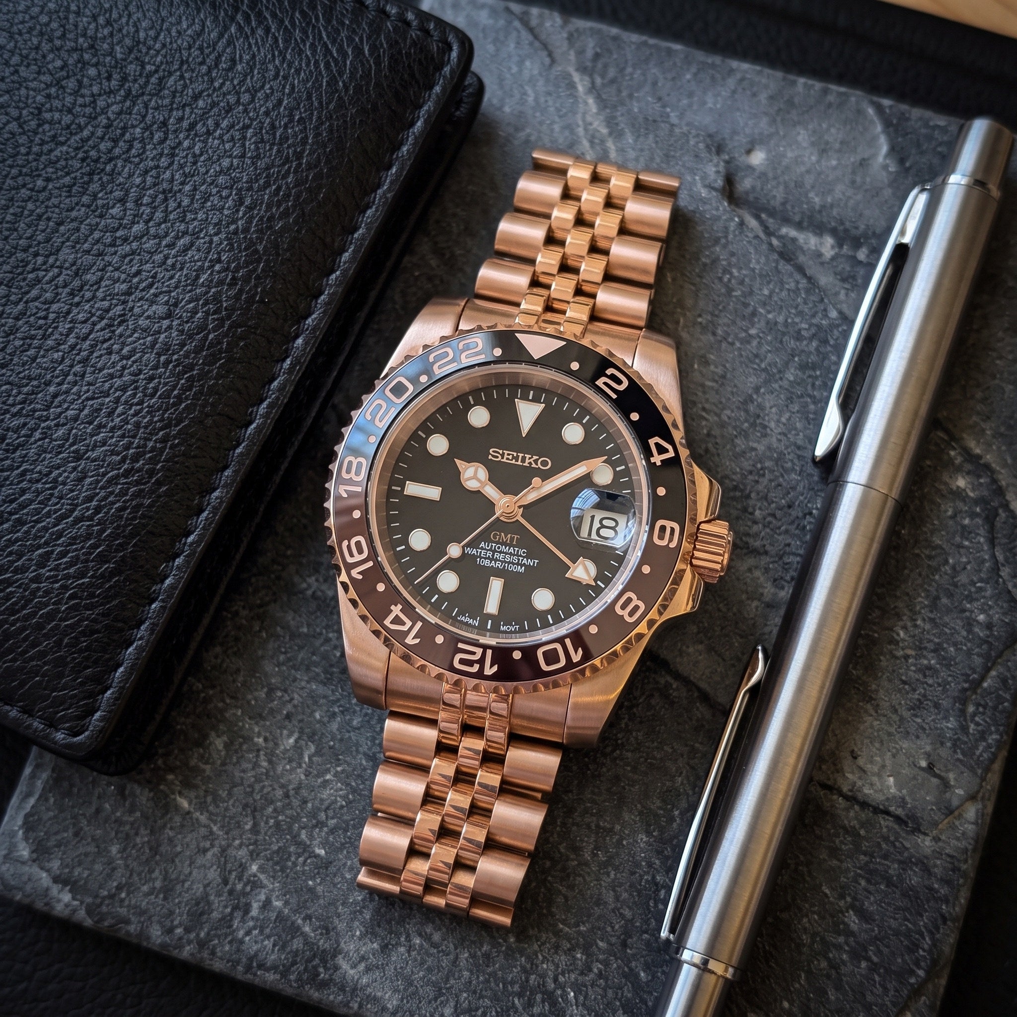 GMT Mod – Rose Gold · Brown-Black Bezel · Jubilee – 40mm – Automatic GMT – lifestyle flat lay