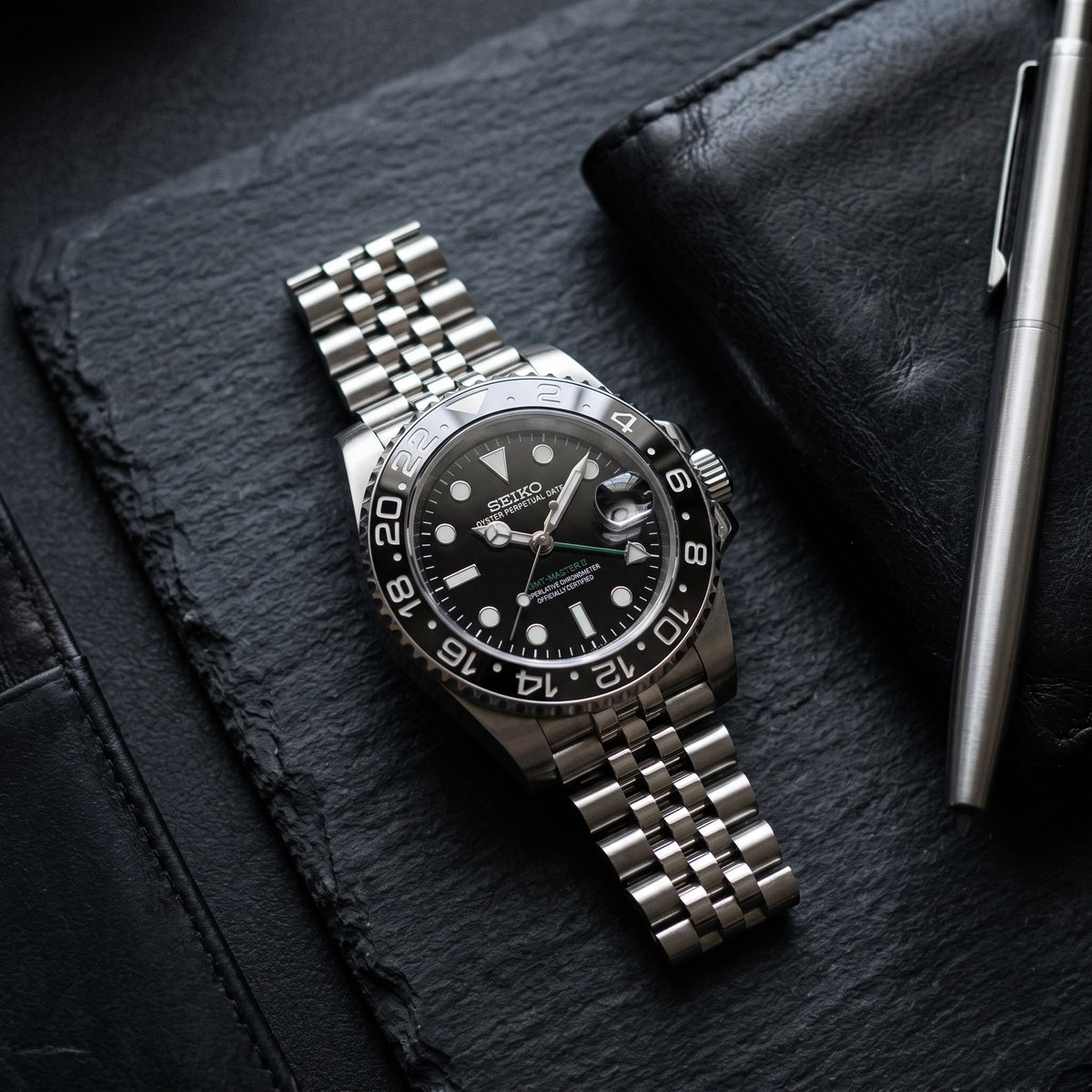 GMT Mod – Steel · Black-Grey Bezel · Jubilee – 40mm – Automatic GMT – lifestyle flat lay
